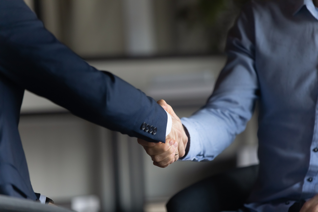 Two Businessmen In Formal Suits Shaking Hands After Successful Negotiations